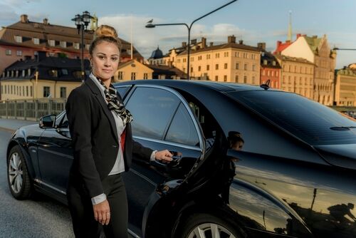 Chauffeur puts luggage in the trunk while guest waits.